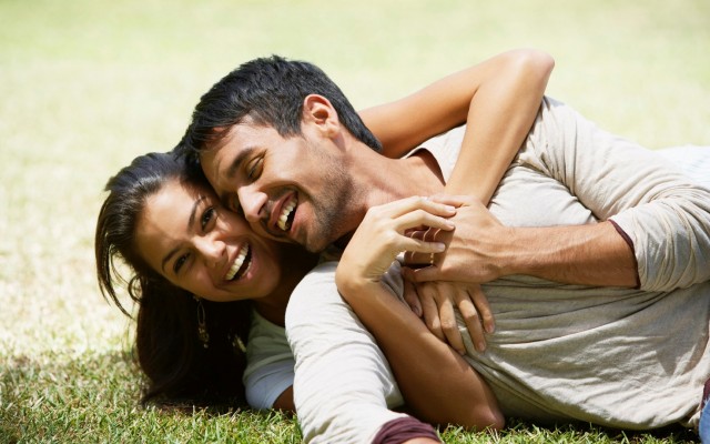 South American couple laying in grass